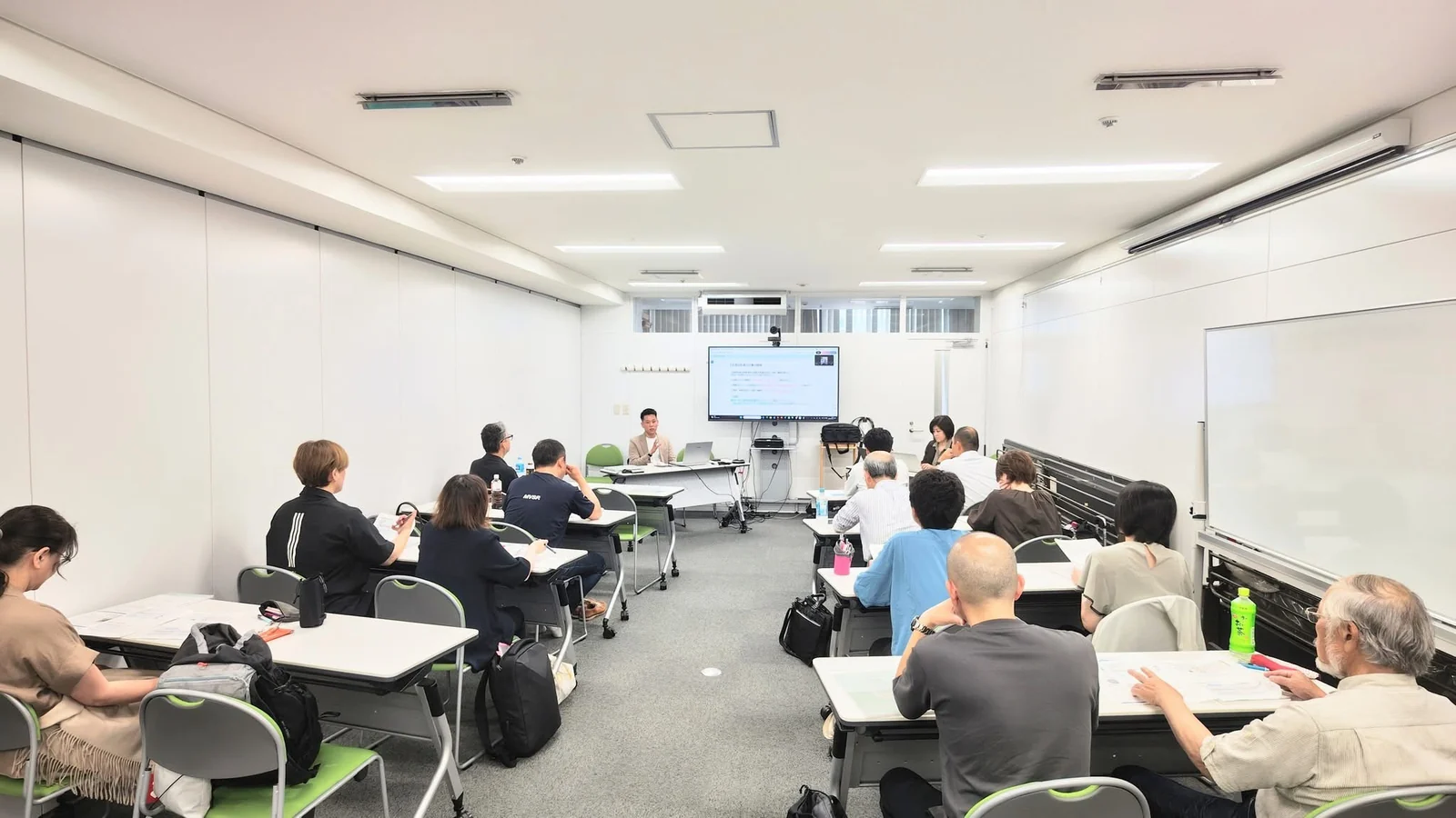 スクリーンのある会場で講師の話を聞く参加者の全景